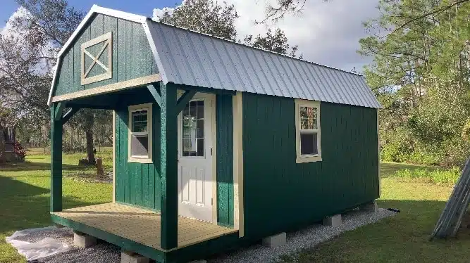 a green 14x24 cabin shed with a metal roof, beige trim, and a white door for sale in florida
