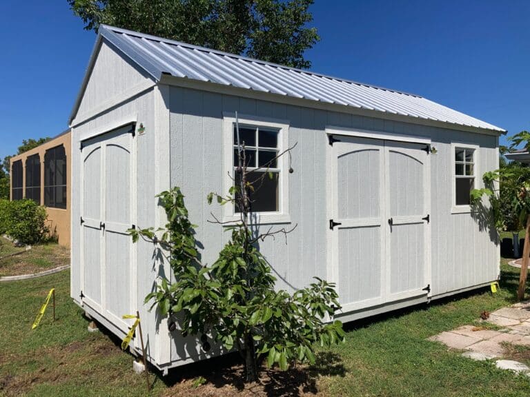 white lofted side gable shed with two windows and two sets of double doors