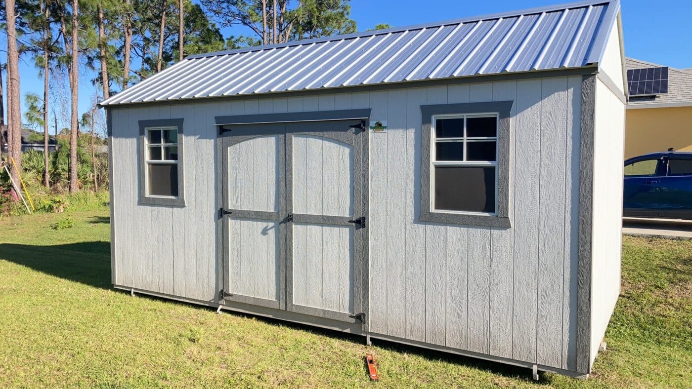 white side gable shed with grey trim, two windows, and a double door