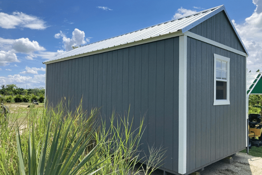 gray and white trimmed side lofted gable shed by plants
