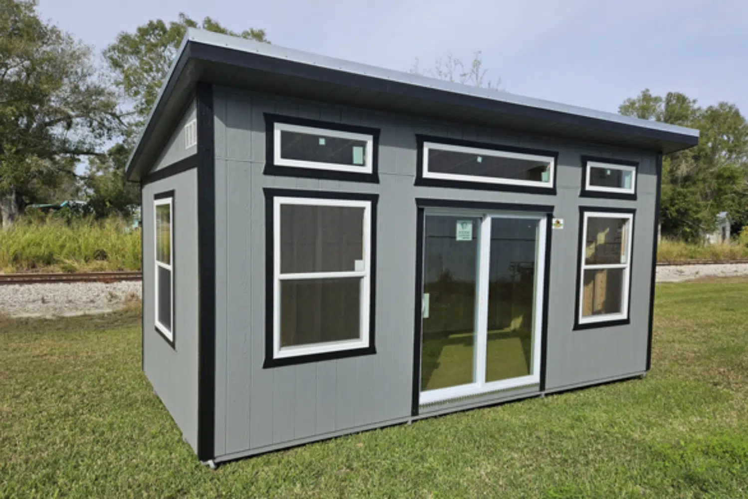 gray studio sheds in loxahatchee fl with multiple large clear windows and black trim