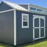 a grey side lofted gable shed with white trim, double doors, two windows, and a dormer up top in lakeport fl