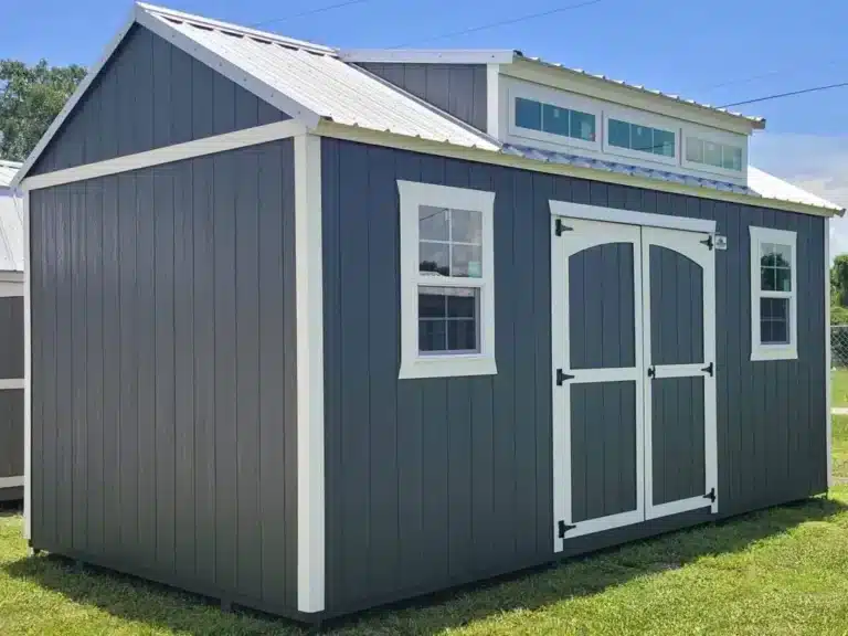 a grey side lofted gable shed with white trim, double doors, two windows, and a dormer up top in lakeport fl