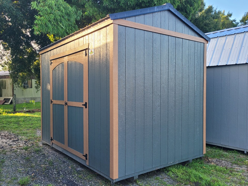 a grey-blueish storage shed with light brown trim with it's back up against another shed in fort lauderdale fl