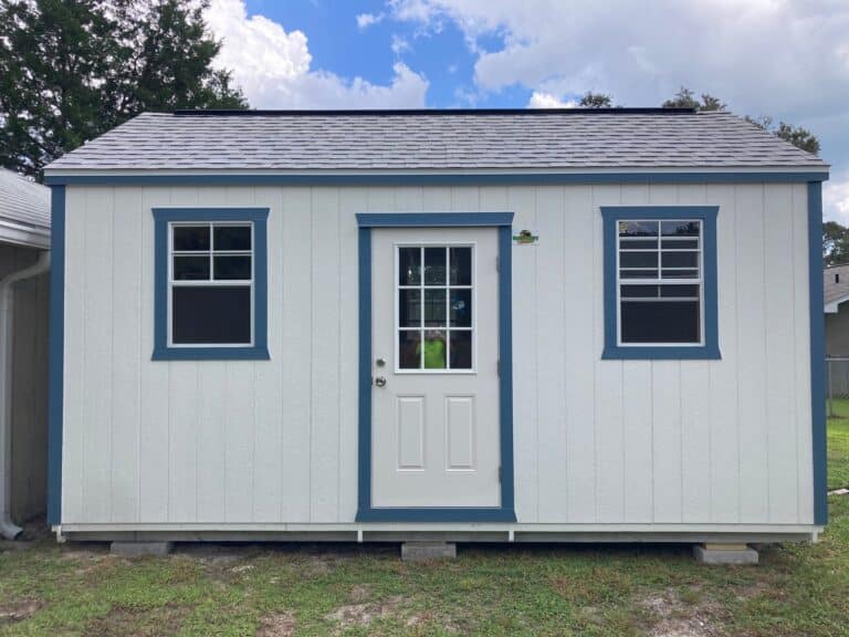 white side gable lofted shed with two windows, blue trim, and a shingle roof