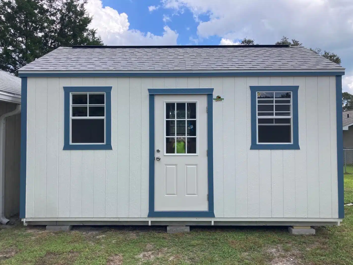 lofted side gable shed with one door, two windows, and blue trim