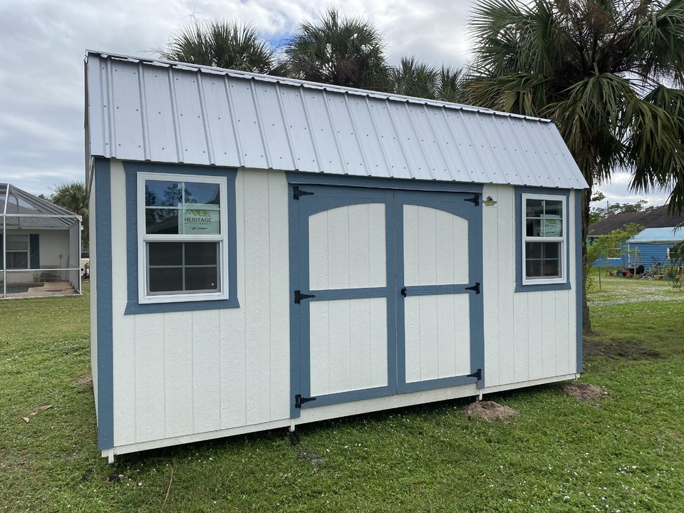 a white barn shed with green trim and a metal roof in clermont fl