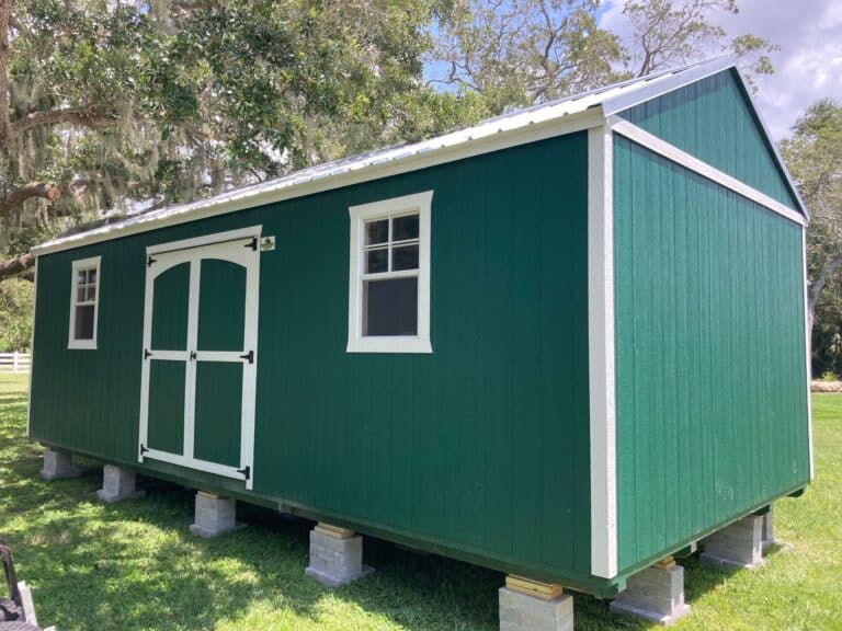 green side gable lofted shed with two windows, double doors, and white trim